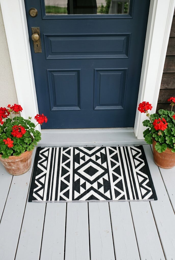 stylish patterned welcome mat on clean front porch entryway